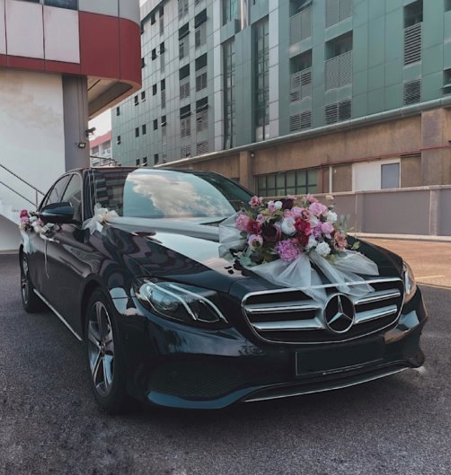 Black Mercedes wedding car dressed with ribbons and florals
